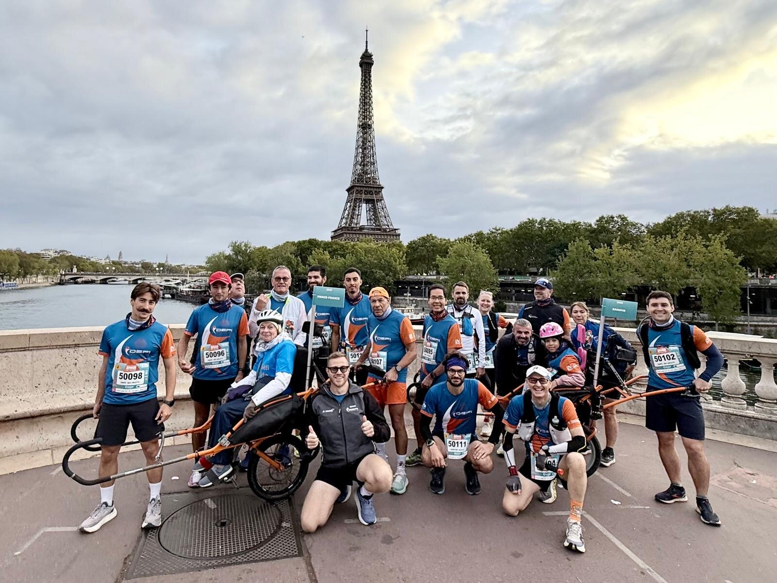 20 km de Paris 2026 — l'équipe réunie avec les deux joëlettes devant la tour Eiffel